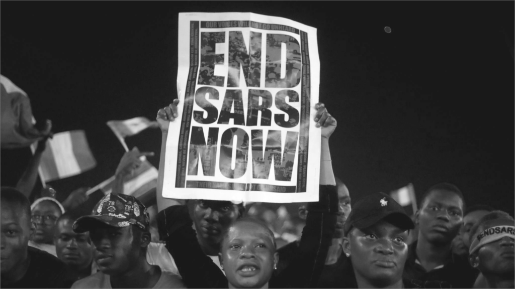 person holding End SARS now poster